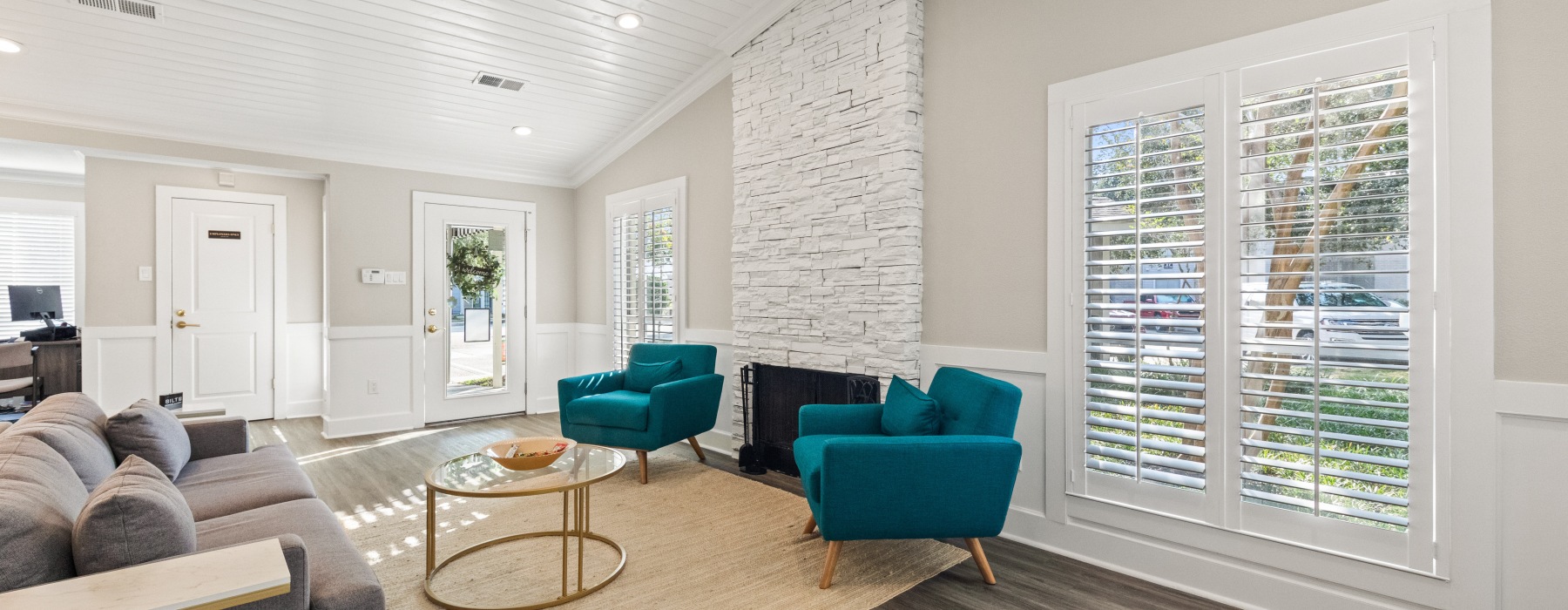 Cozy resident lounge featuring teal accent chairs, fireplace, and natural lighting at apartments in East Baton Rouge.