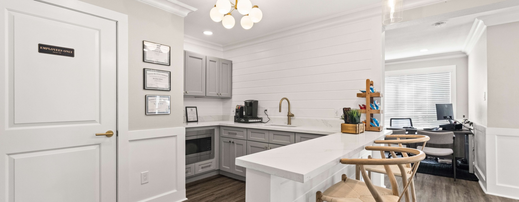 Clubhouse kitchen with bar seating, coffee station, and modern lighting for residents in Baton Rouge apartments.