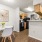 Dining area with modern table set and view into kitchen with wood cabinetry and black appliances.