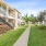 Tree-lined walkway between apartment buildings with private patios and balconies at Baton Rouge apartments.